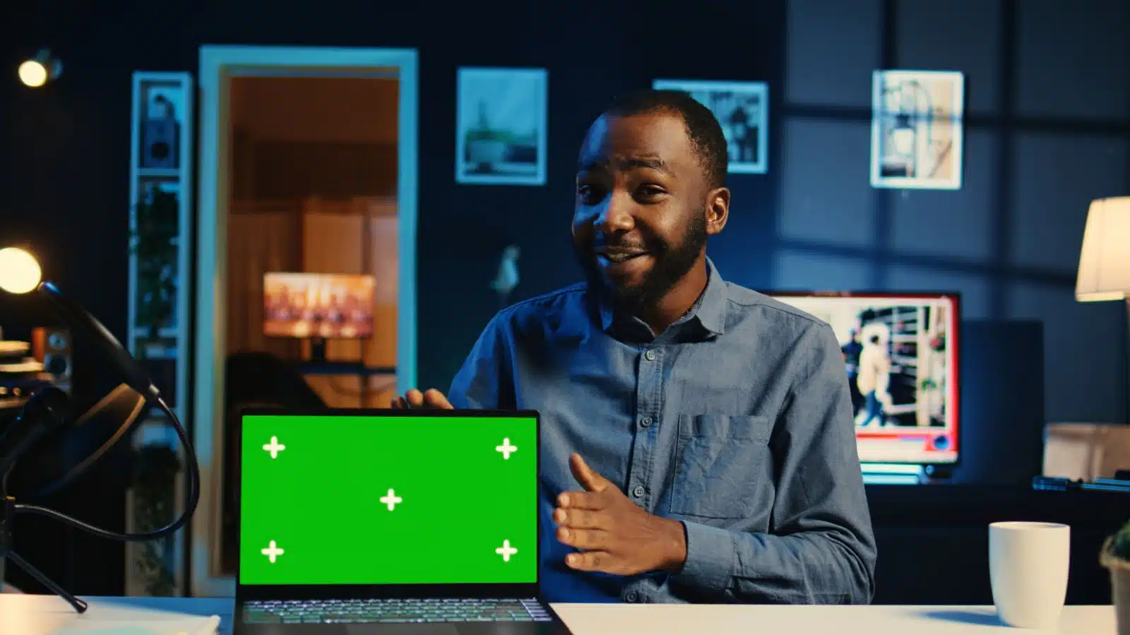 A man shows his laptop with a green screen, representing screen capture technology to answer the question what does a capture card do.