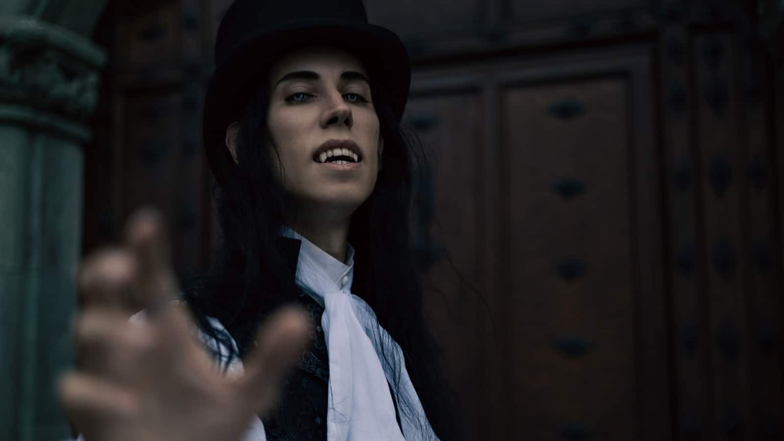 A classy male vampire, reaching out toward the viewer, almost as if begging us to join him. He's well-dressed, but his clothing style looks about a century old.