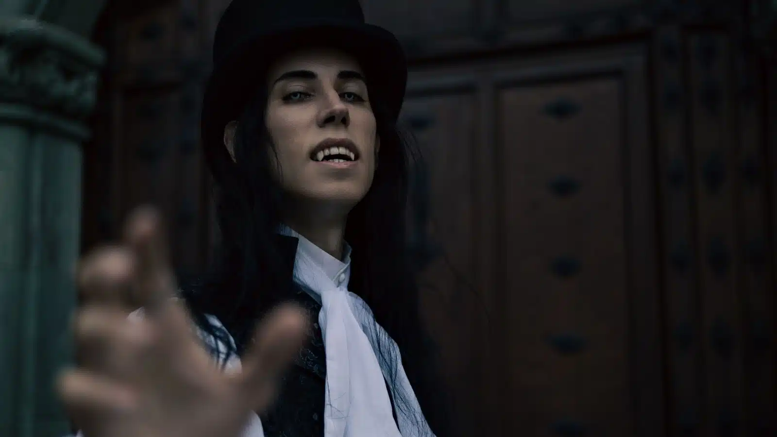 A classy male vampire, reaching out toward the viewer, almost as if begging us to join him. He's well-dressed, but his clothing style looks about a century old.