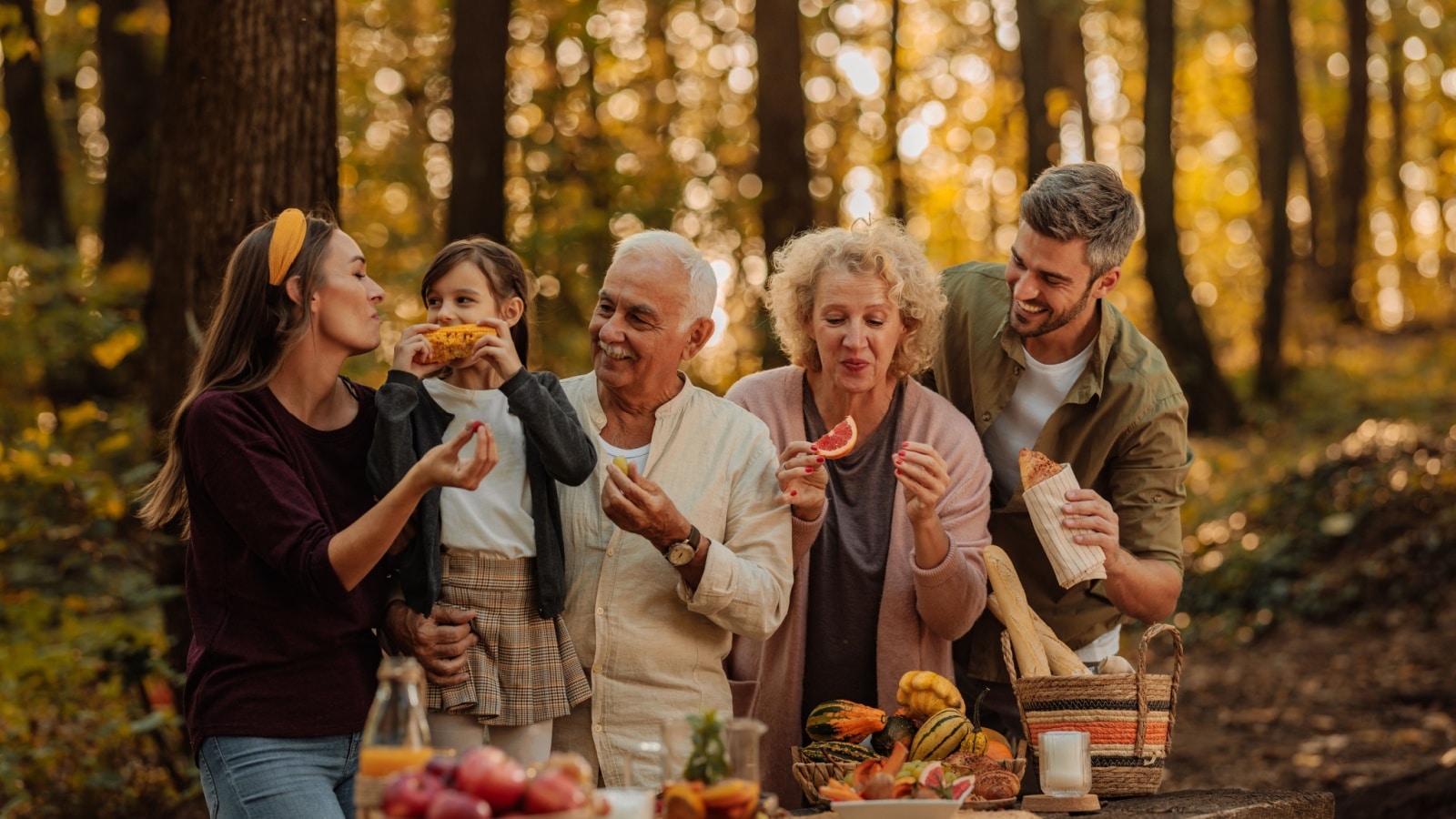 A family enjoying a fall picnic, sampling many of the best autumn flavors.