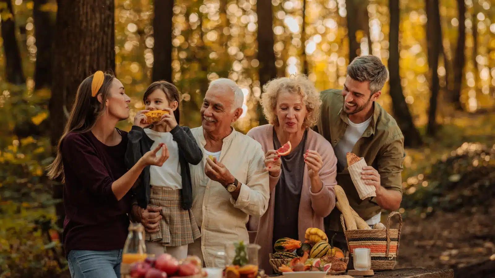A family enjoying a fall picnic, sampling many of the best autumn flavors.