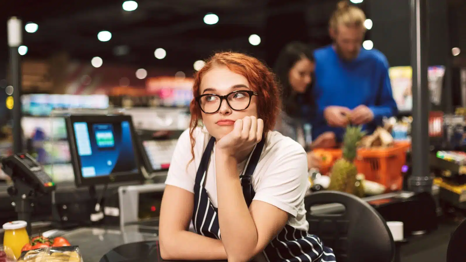 A bored retail worker waiting for customers at her checkout line.