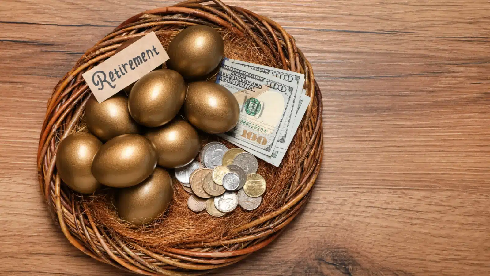 A bird's nest labeled "retirement" with golden eggs and cash inside to represent a nest egg. 
