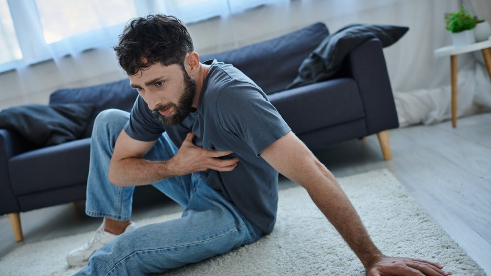A terrified man sits on the floor clutching his chest to represent weird phobias.