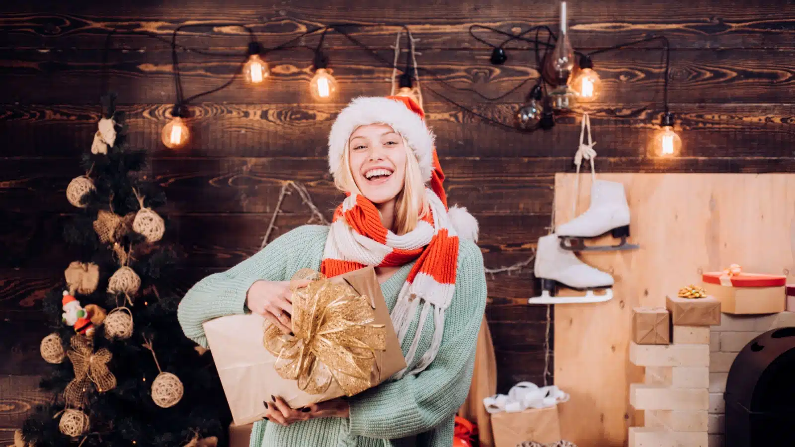 A smiling woman holds a Christmas gift to represent the question what do I want for Christmas?