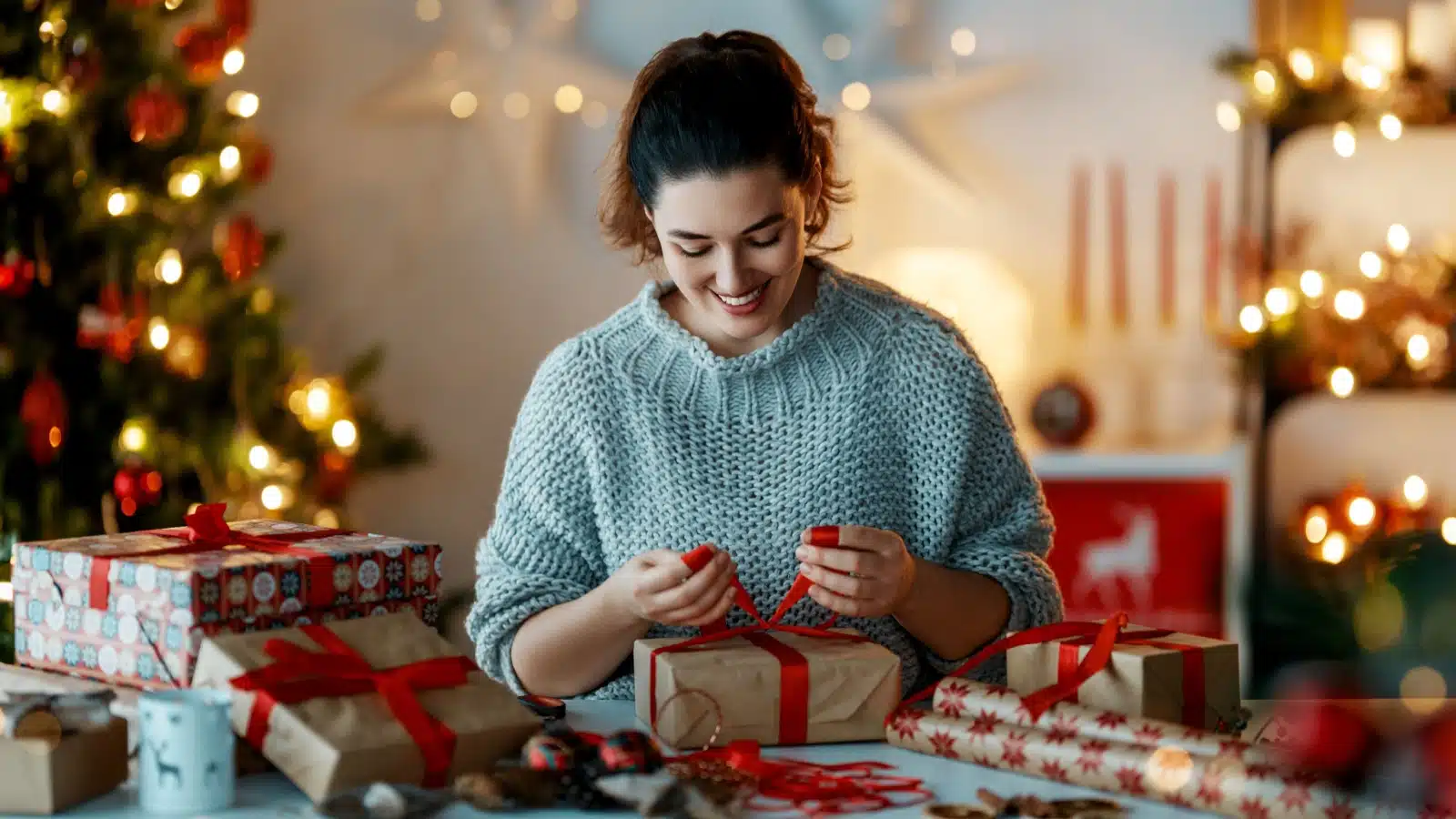 A happy woman wraps Christmas presents.