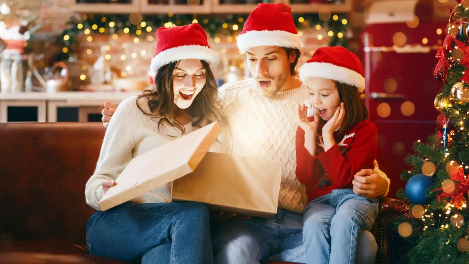A mom opens her gift with her daughter and husband.