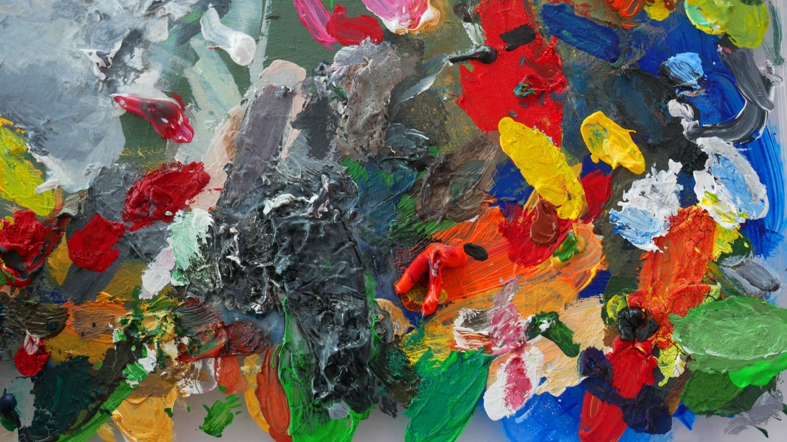 A bright, messy, artist's palette showing both warm and cool colors. 