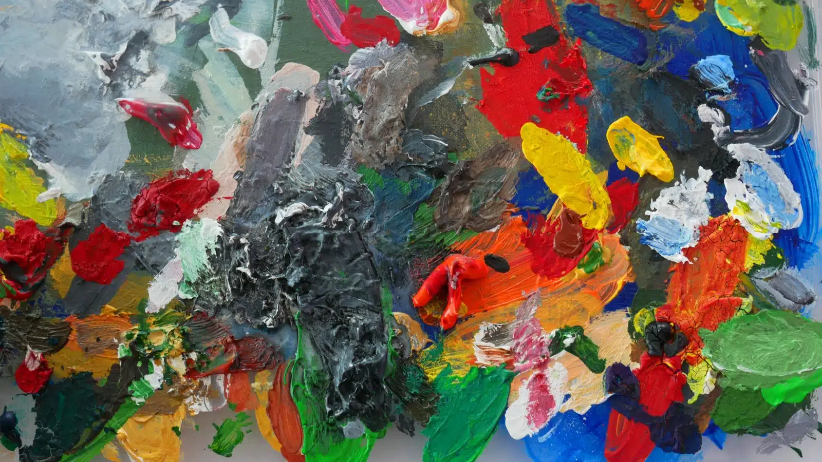 A bright, messy, artist's palette showing both warm and cool colors.