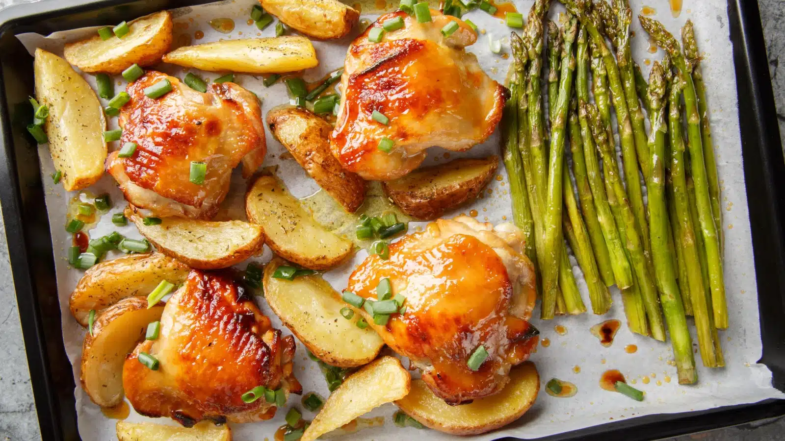 A pan of baked chicken thighs and asparagus.