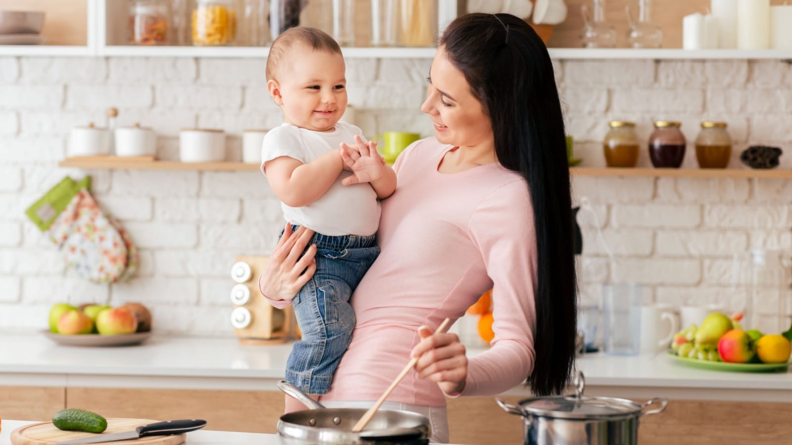 A mom holding her baby while cooking to represent easy dinner ideas.
