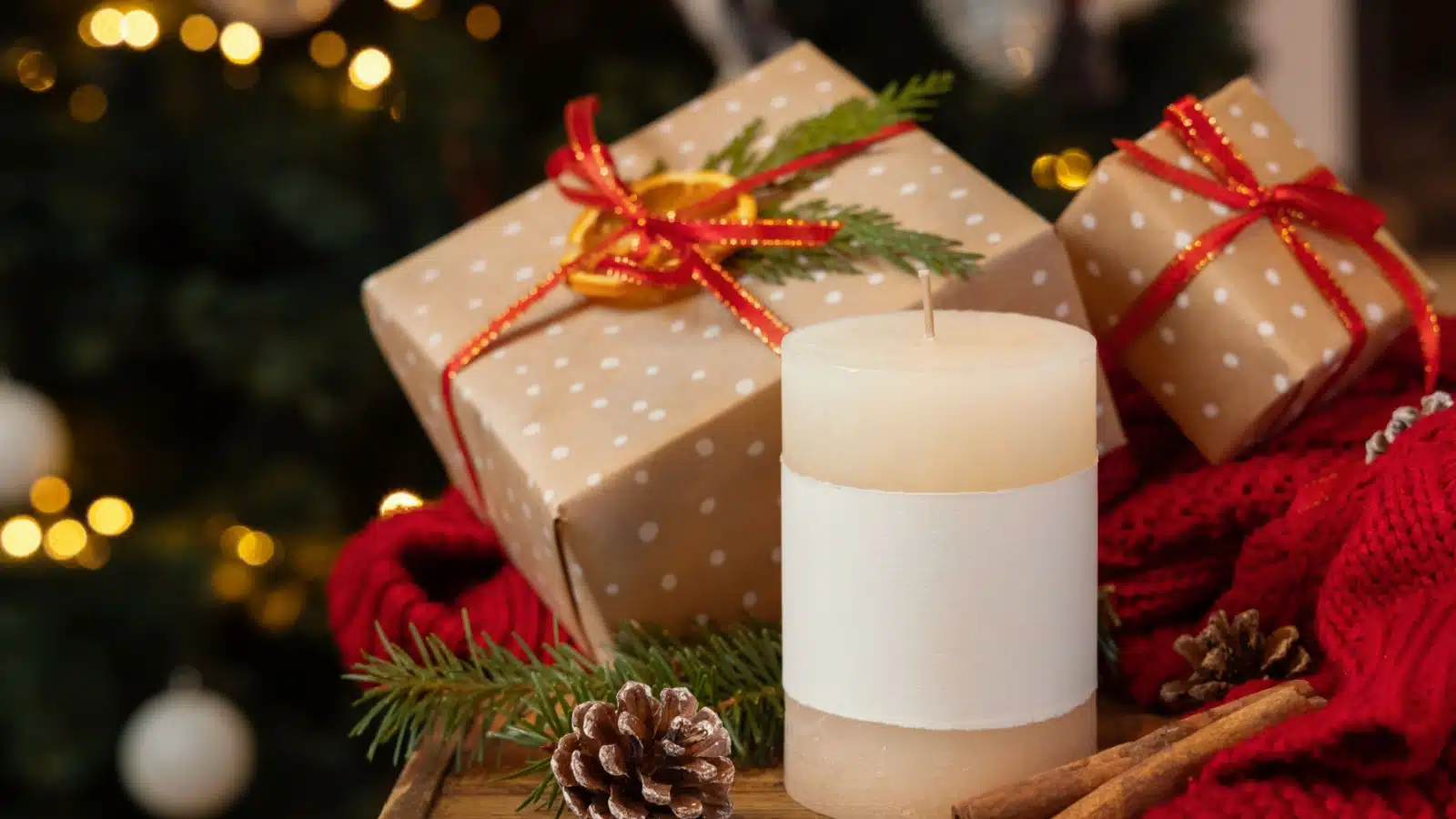 A candle in front of two wrapped Christmas presents.