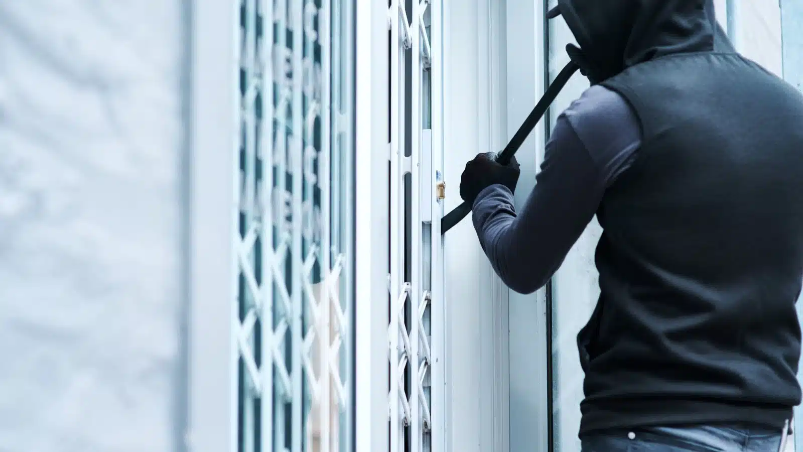 A burglar uses a crowbar to get a door open.