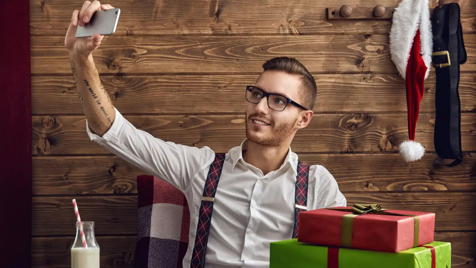 A man taking a selfie with Christmas gifts.