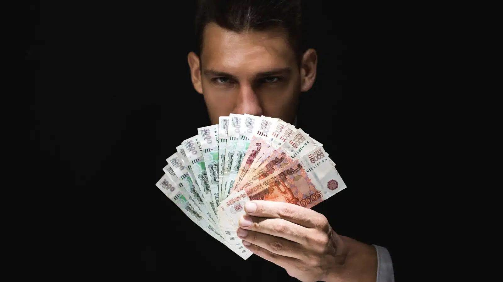 A mysterious looking man shows off a handful of Russian currency.
