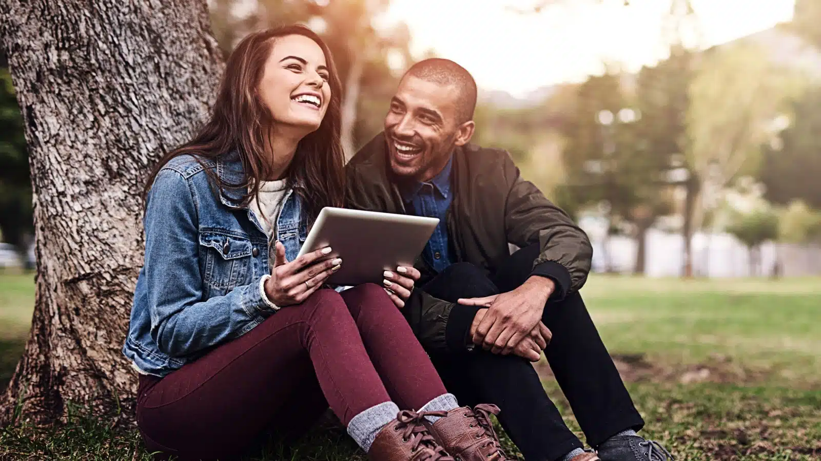 A happy couple in a park using a reading tablet.