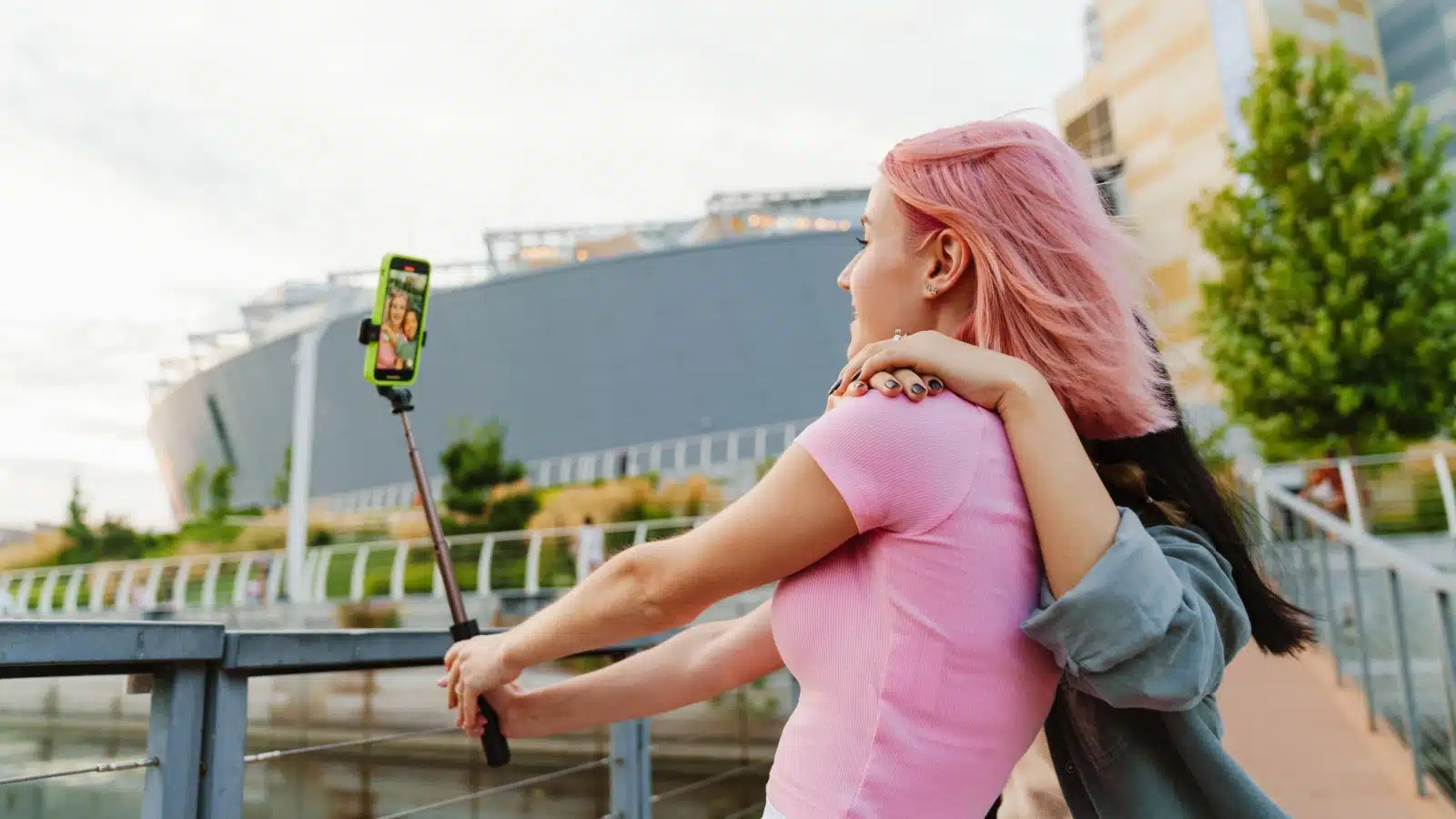 Two girls use a selfie stick to take a photo.