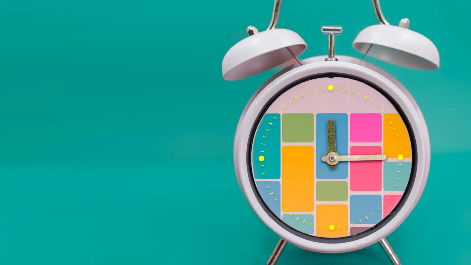 An old-fashioned alarm clock with colorful blocks of time filled out to represent the time blocking time management technique.