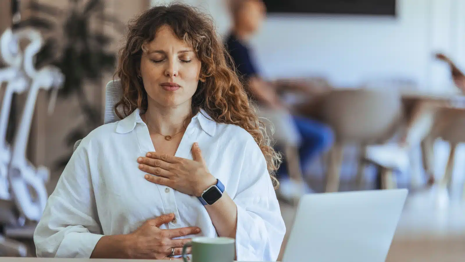 A woman slows down by taking a deep breath while working to represent time management techniques.