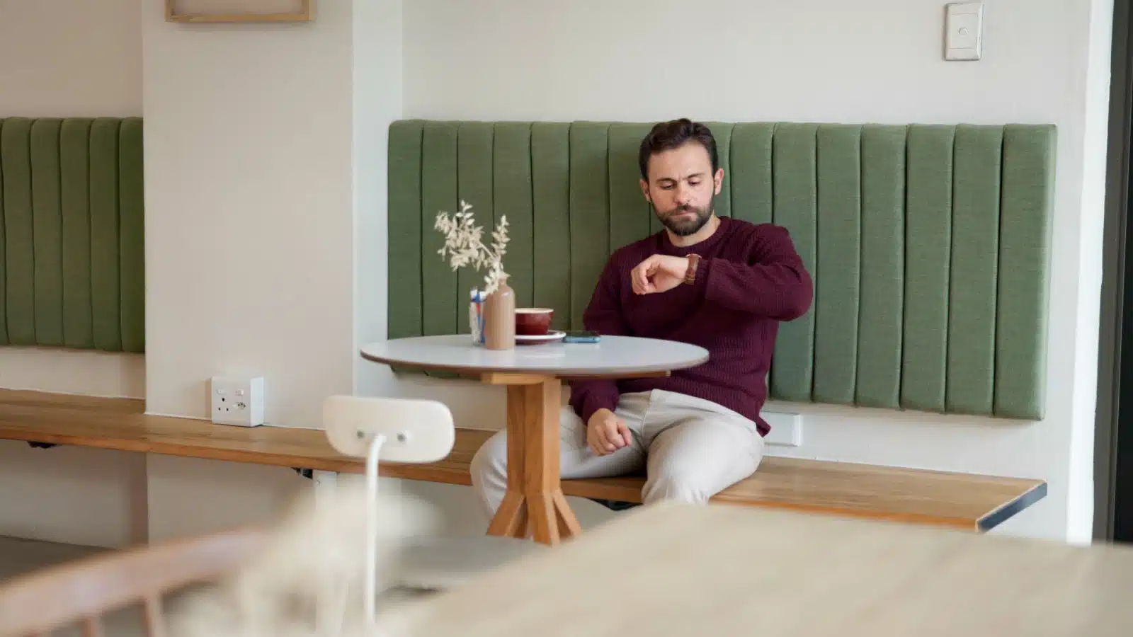 A man looks at his watch while waiting for someone in a cafe.