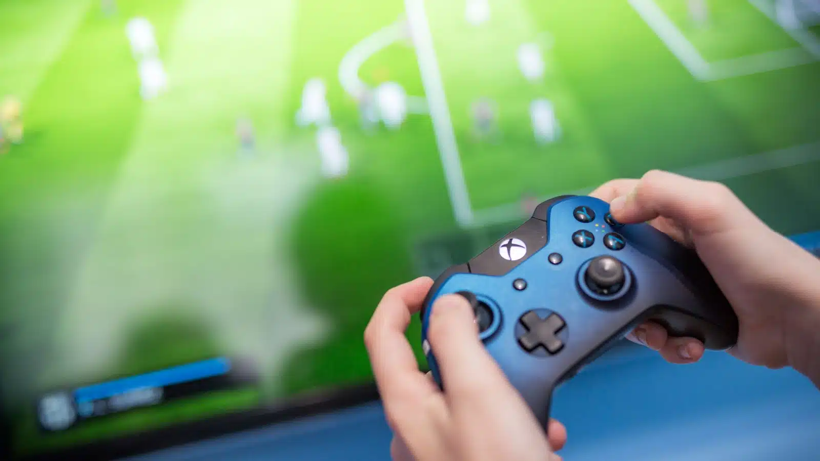 A gamer plays a modern version of FIFA using an Xbox controller.
