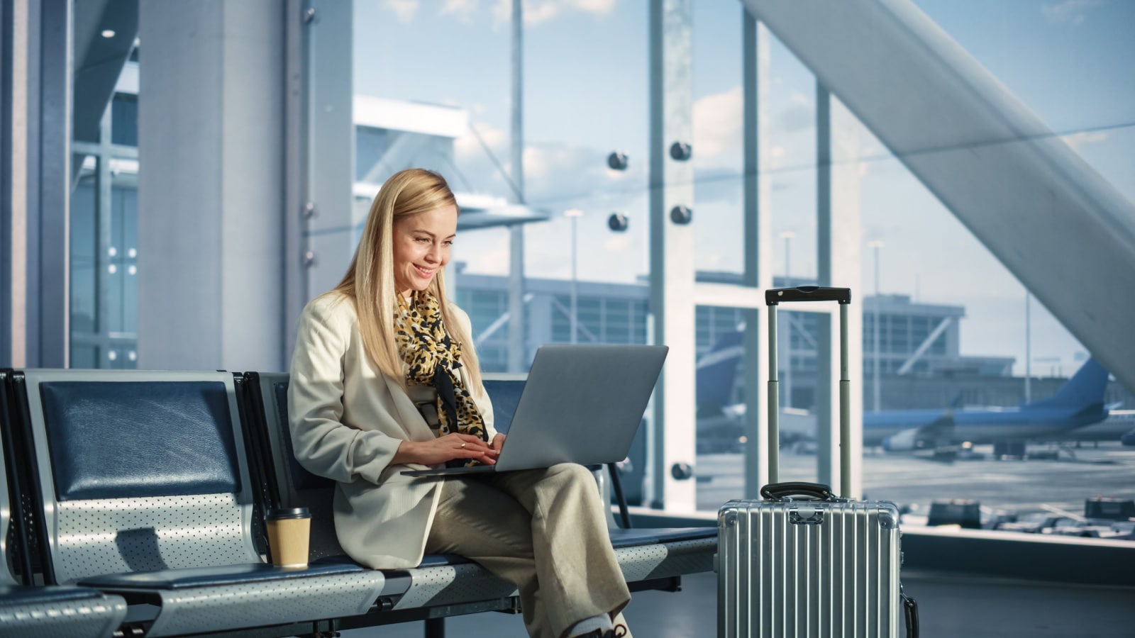 A businesswoman works on her laptop in an airport terminal. 