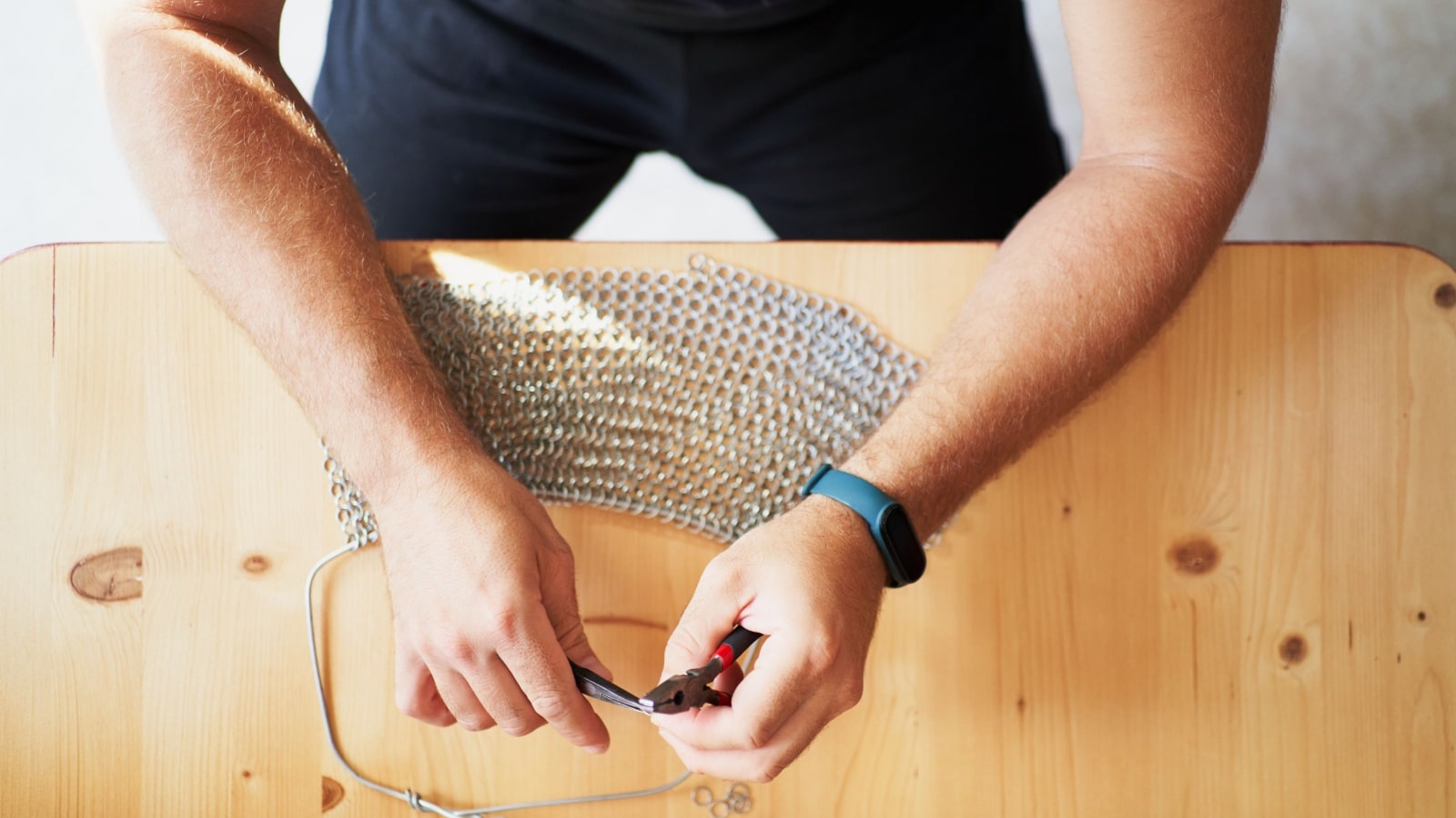A person making chain mail to represent unique hobbies.