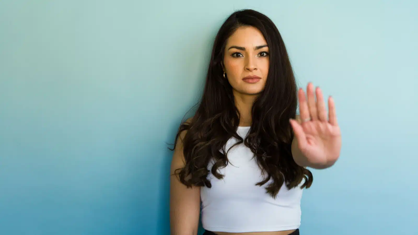 A confident woman puts her hand up to say no after setting a boundary.