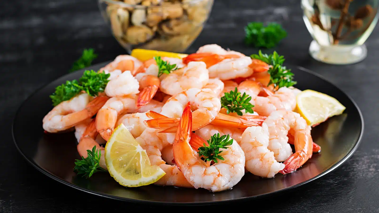 A plate of cooked shrimp with the tails on.