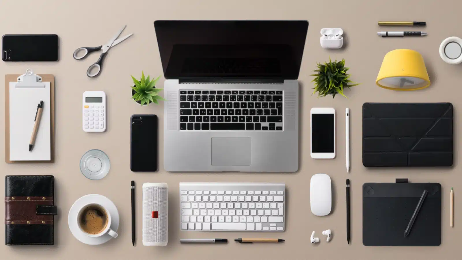 Flat top view of a desk filled with items for productivity, like a list, pens, laptop, keyboard, and more.