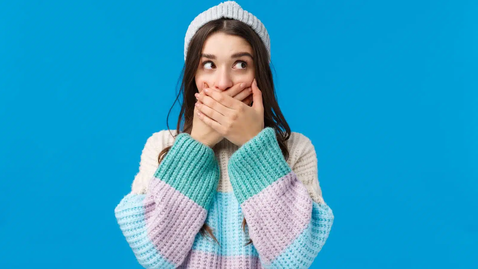 A woman covers her mouth in embarrassment after saying something she didn't mean.