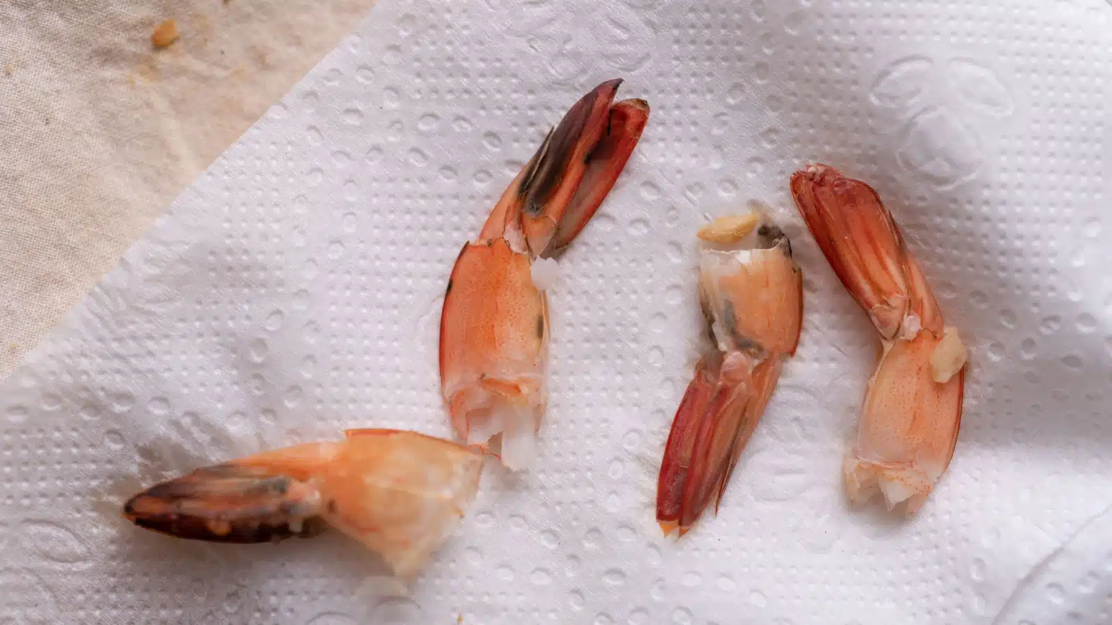 Four discarded, gross looking shrimp tails on a napkin.