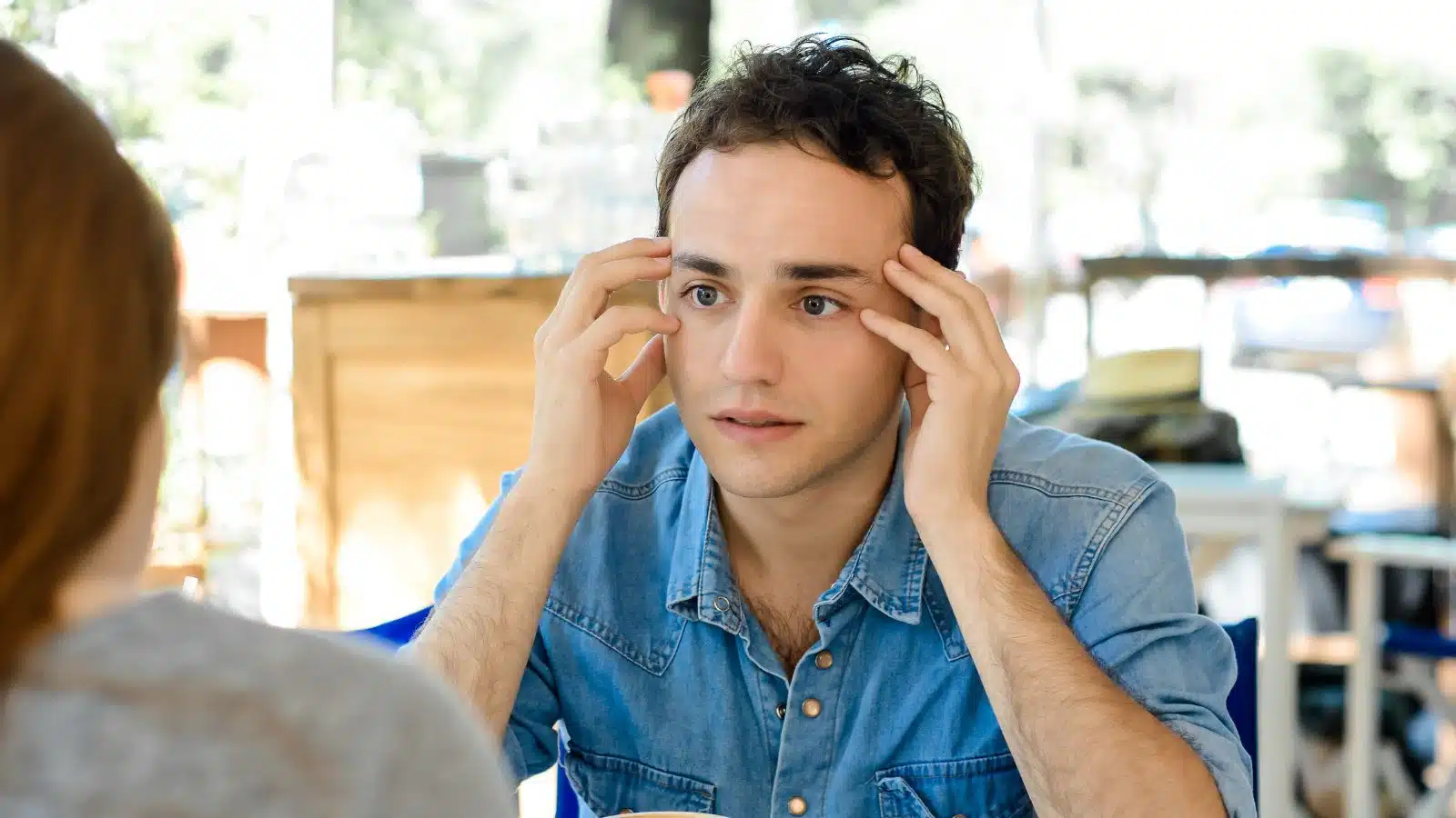 A man looks anxious and disturbed during a coffee shop date.