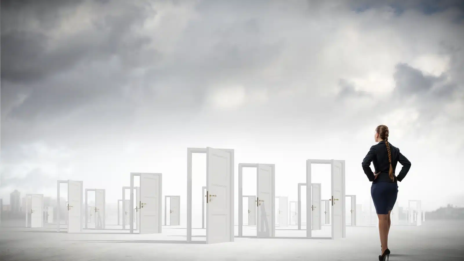A businesswoman stands in an ethereal setting looking at all the open doors in front of her. Each open door represents an opportunity.