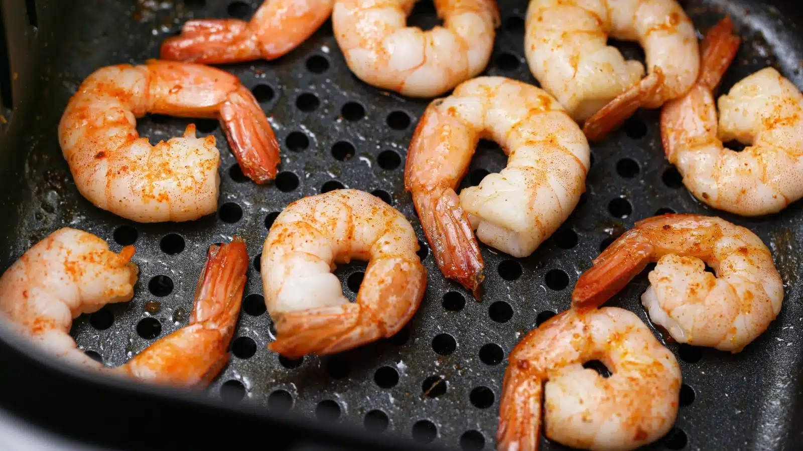Shrimp with tails cooking in an air fryer.