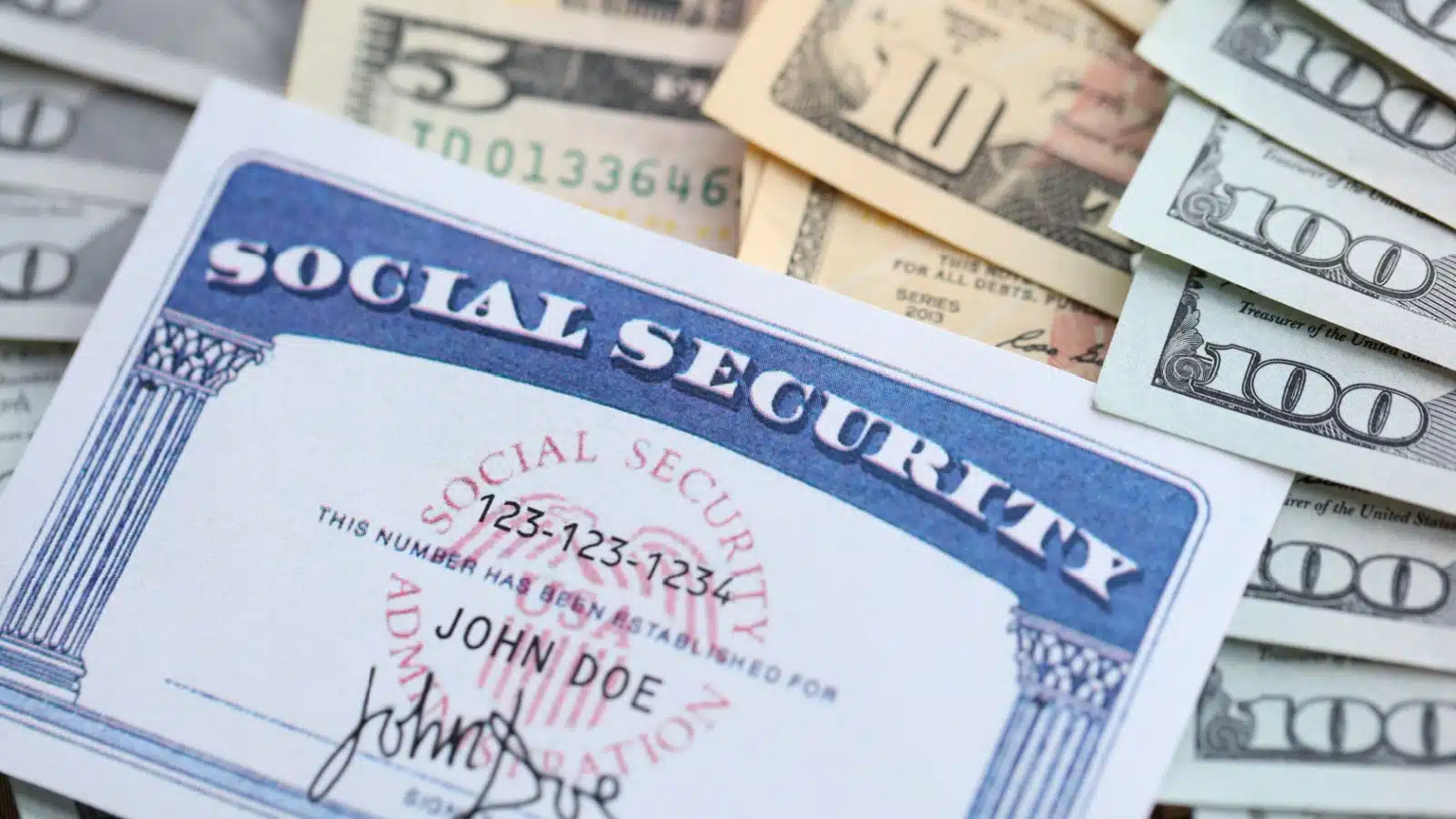 A social security card rests on a pile of money.