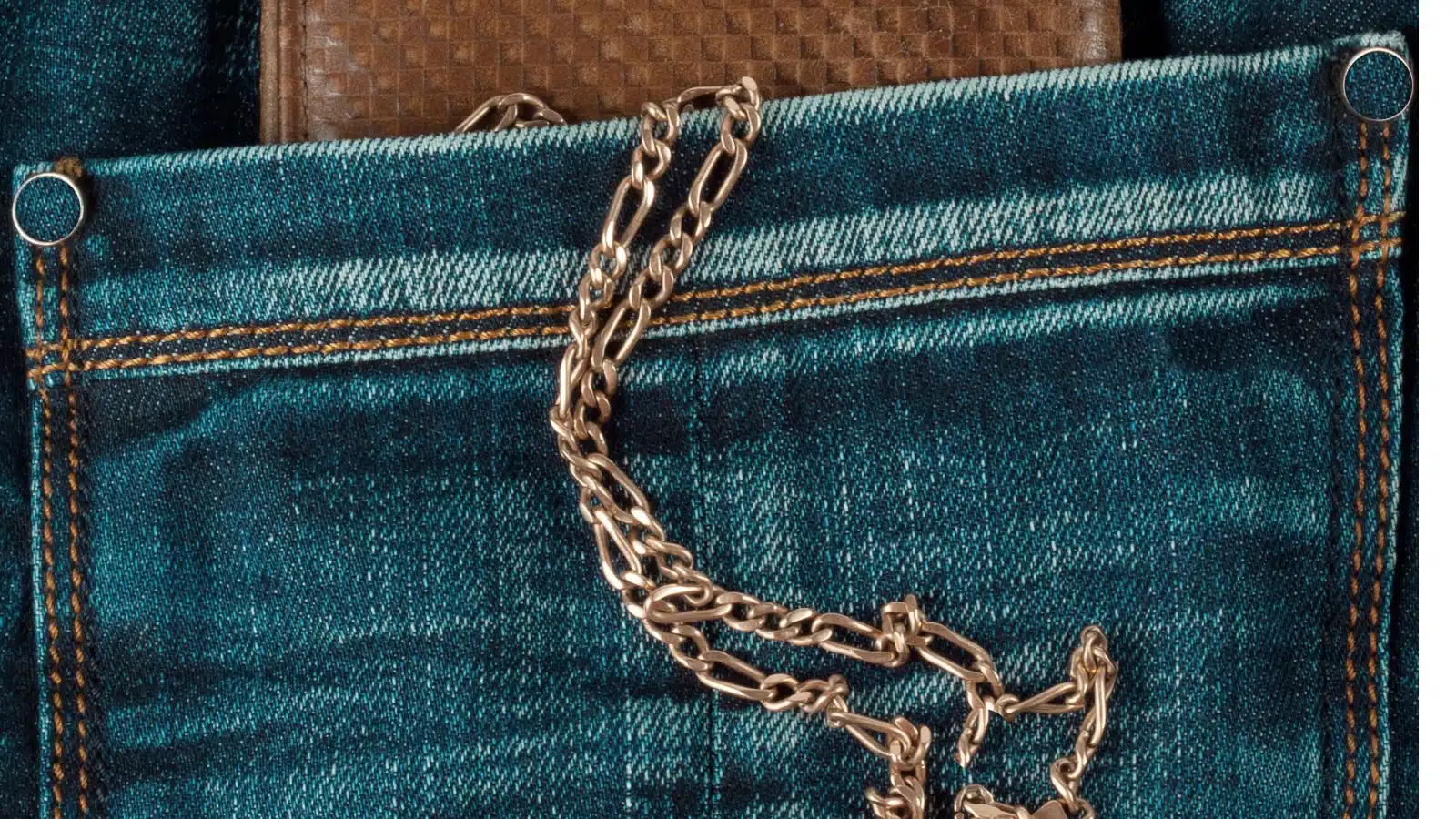Close up of a wallet on a chain in the back pocket of jeans. 