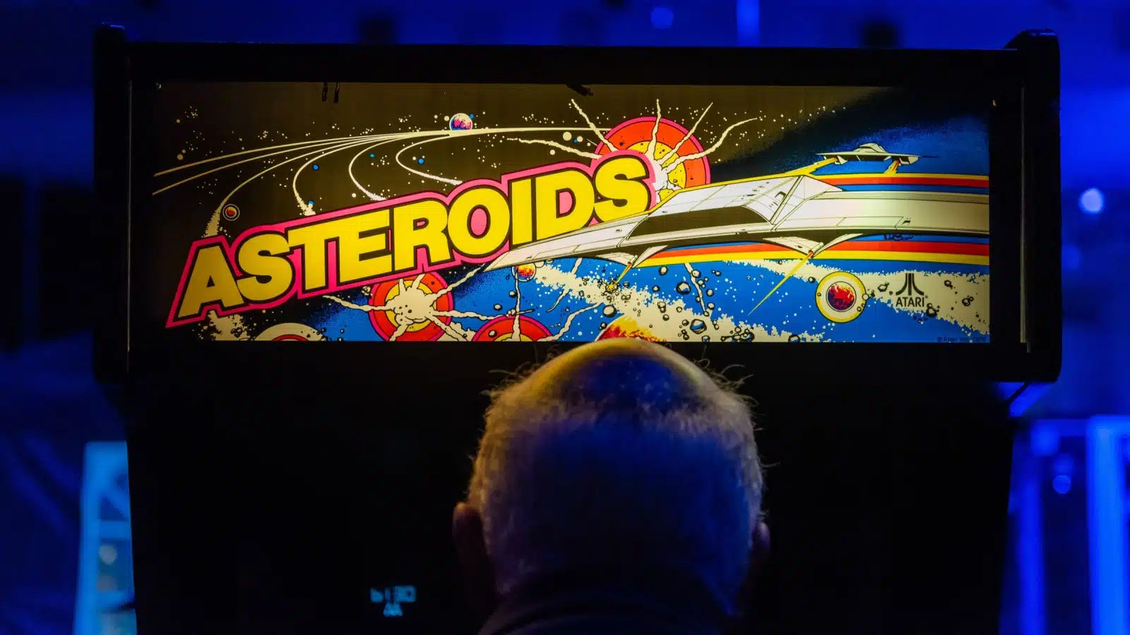 A man plays Asteroids on an arcade cabinet.