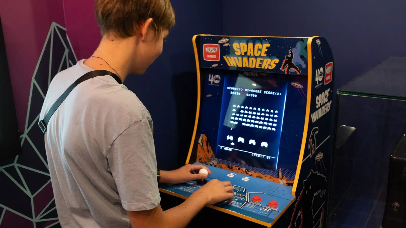 A teenager plays Space Invaders on an Arcade cabinet.