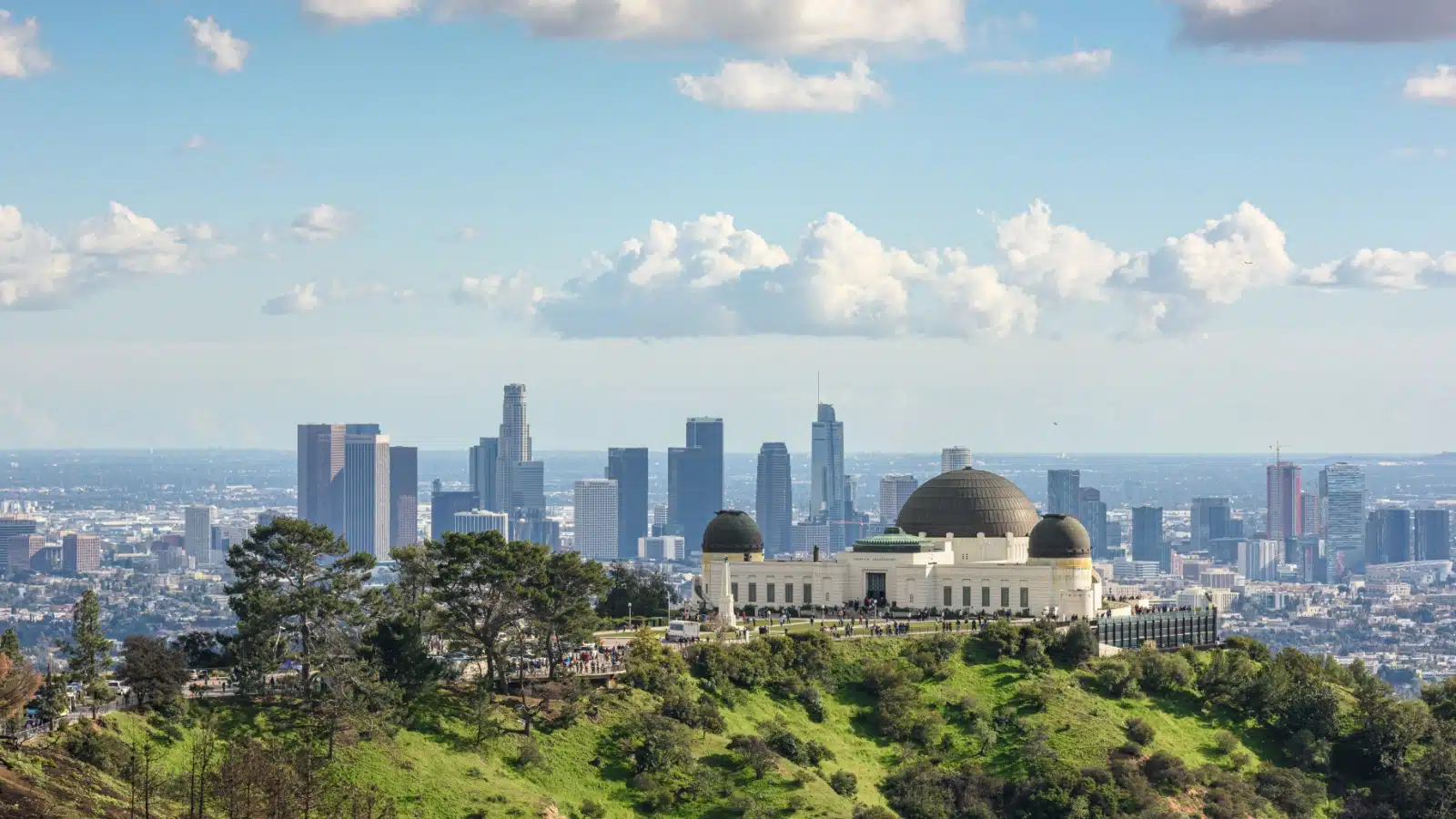The Griffith Observatory on a sunny day with the city skyline in the background.