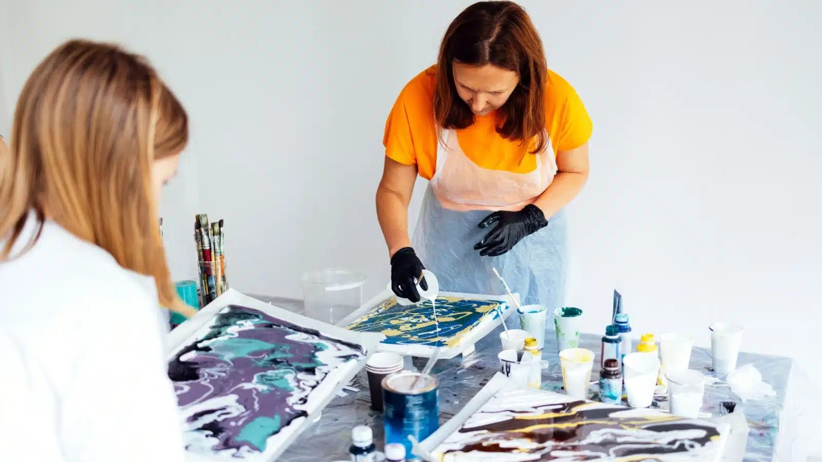 A woman shows how to make art using acrylic swirls.