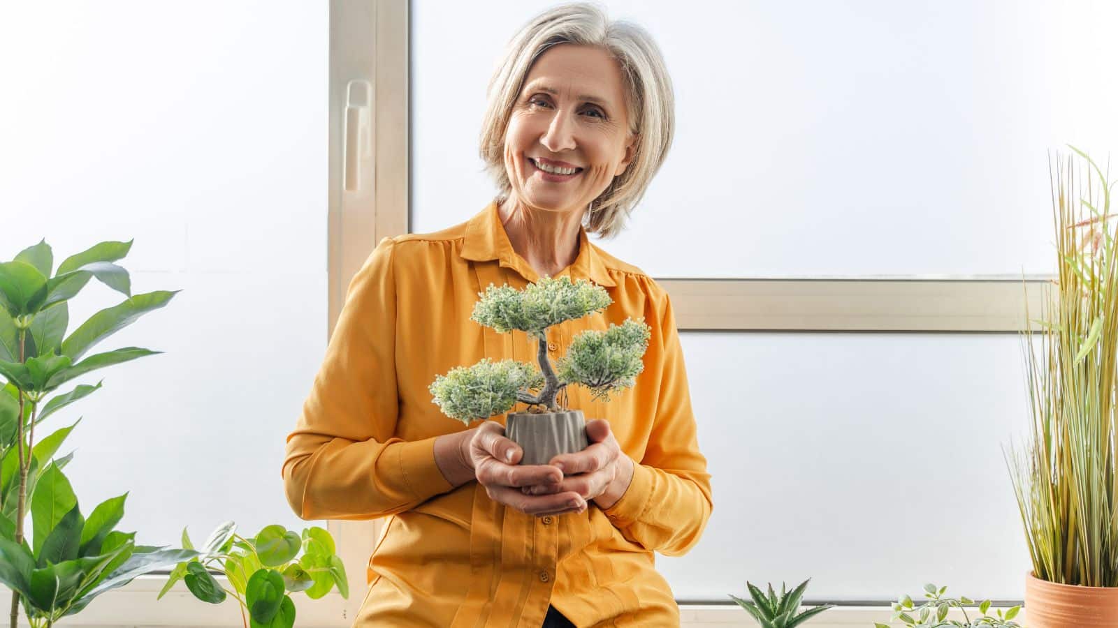 A woman holds up her bonsai plant, showing off her unique hobby.