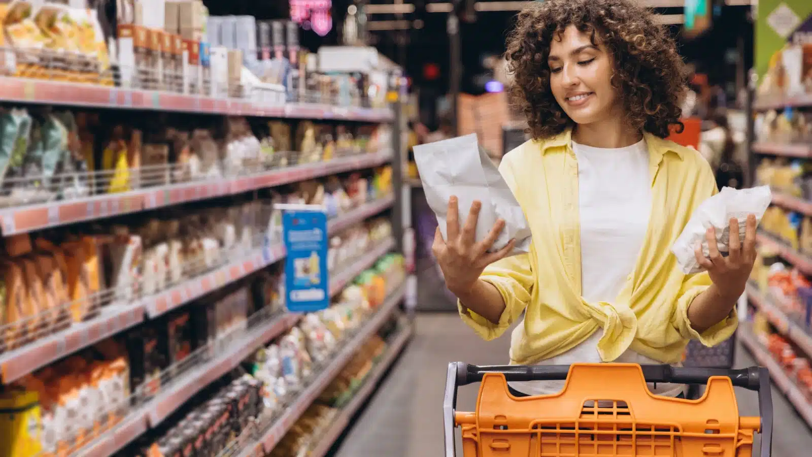 A woman compares generic vs name brand grocery store products, deciding what to buy. 