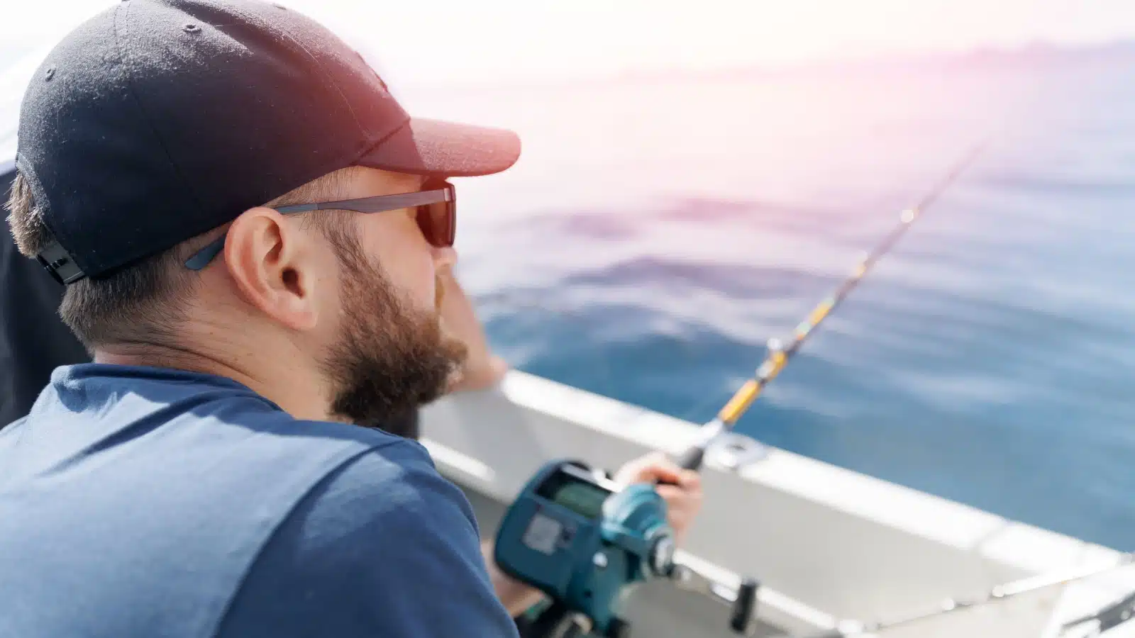 A man holds a fishing pole while deep sea sport fishing.