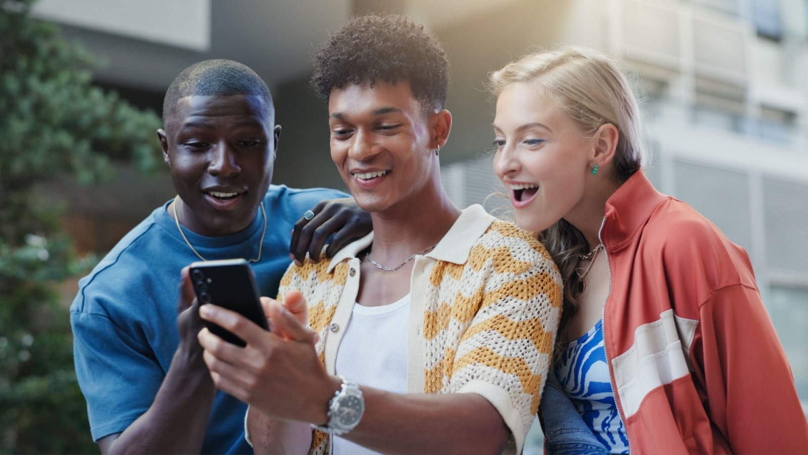 A group of excited friends looking at someone's phone.