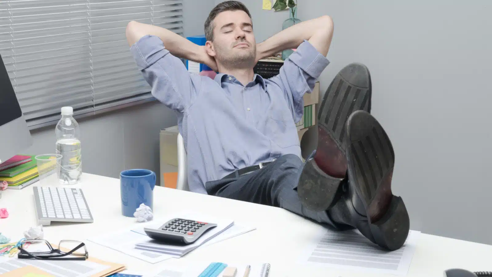 A lazy man kicks back his feet and rests while he's supposed to be working.