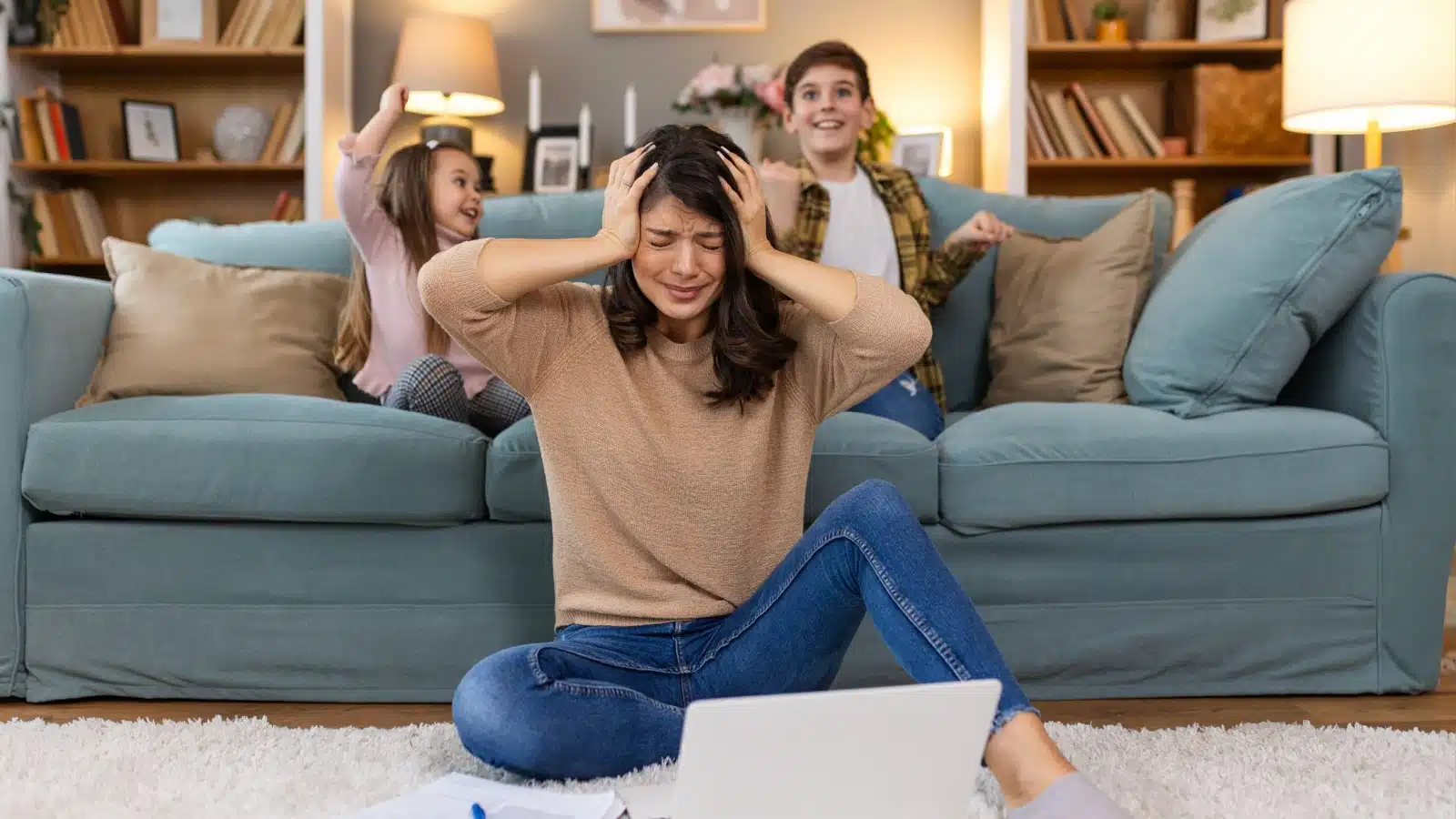 A woman tries to work from her laptop at home, but her kids are a constant, annoying distraction.