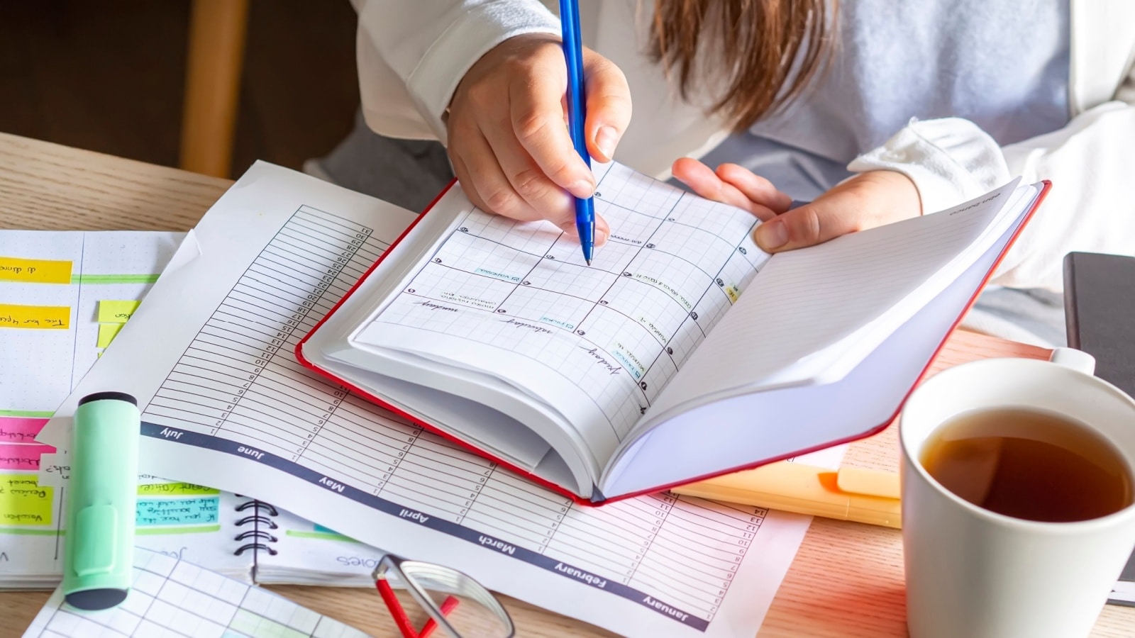 A woman using various productivity tools to represent the best productivity printables and printable planners.