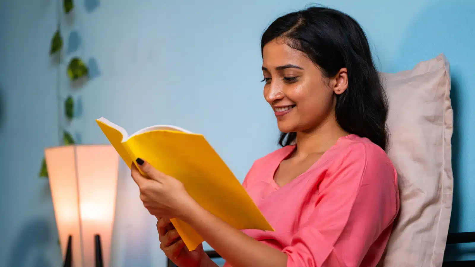 A woman reads documents in a folder before going to bed.
