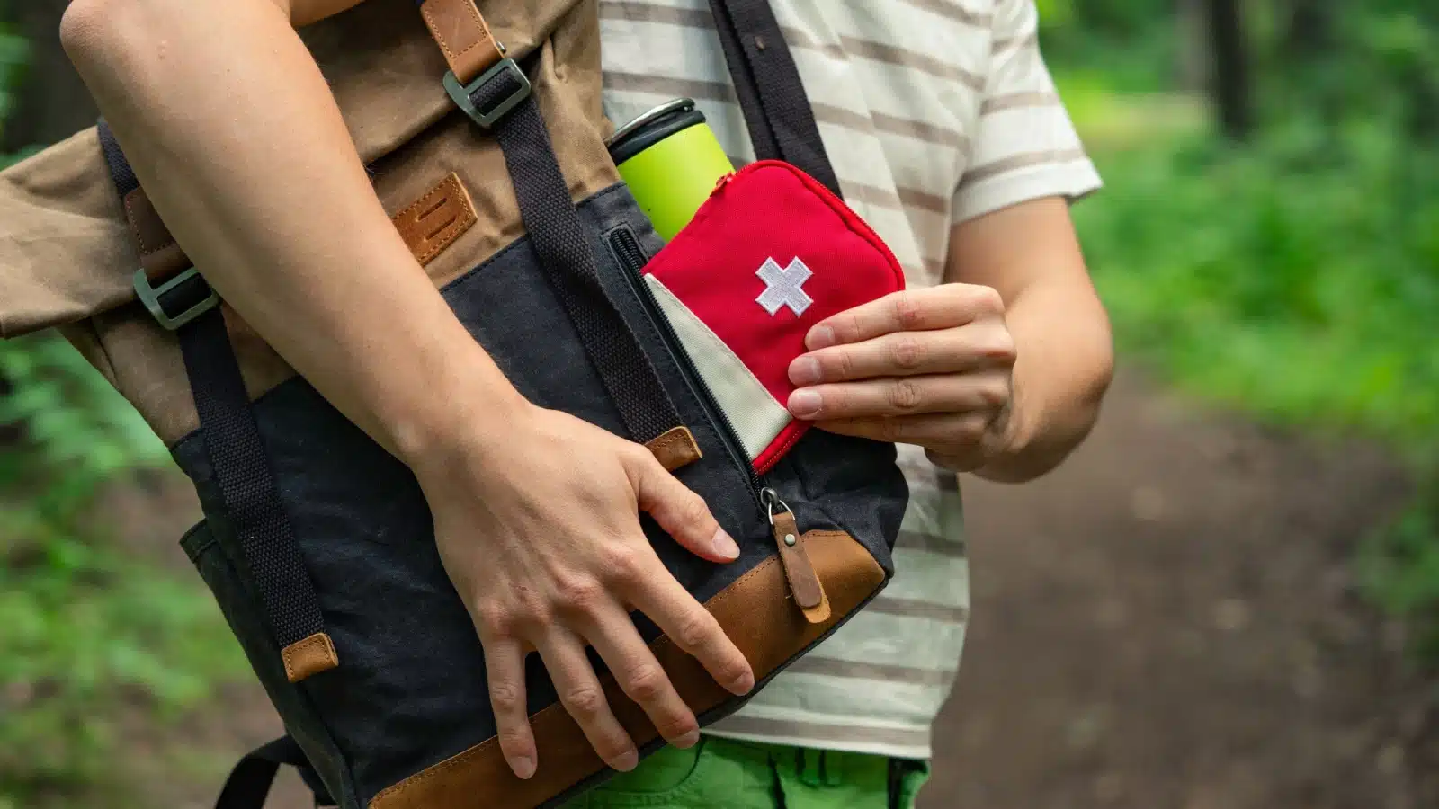 A hiker pulls a first aid kit out of their bag.